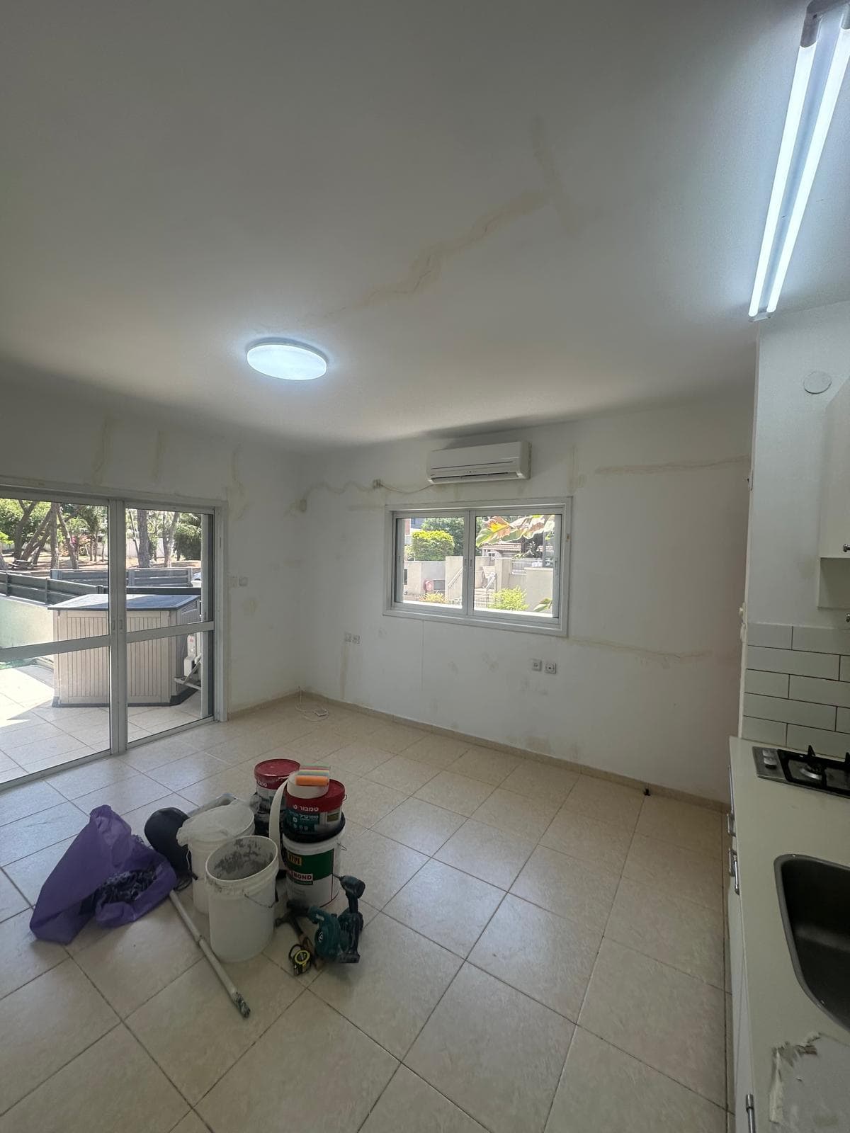 סלון ומטבחון בדירה, קירות עם תיקוני שפכטל לפני צבע ודליי צבע על הרצפה
